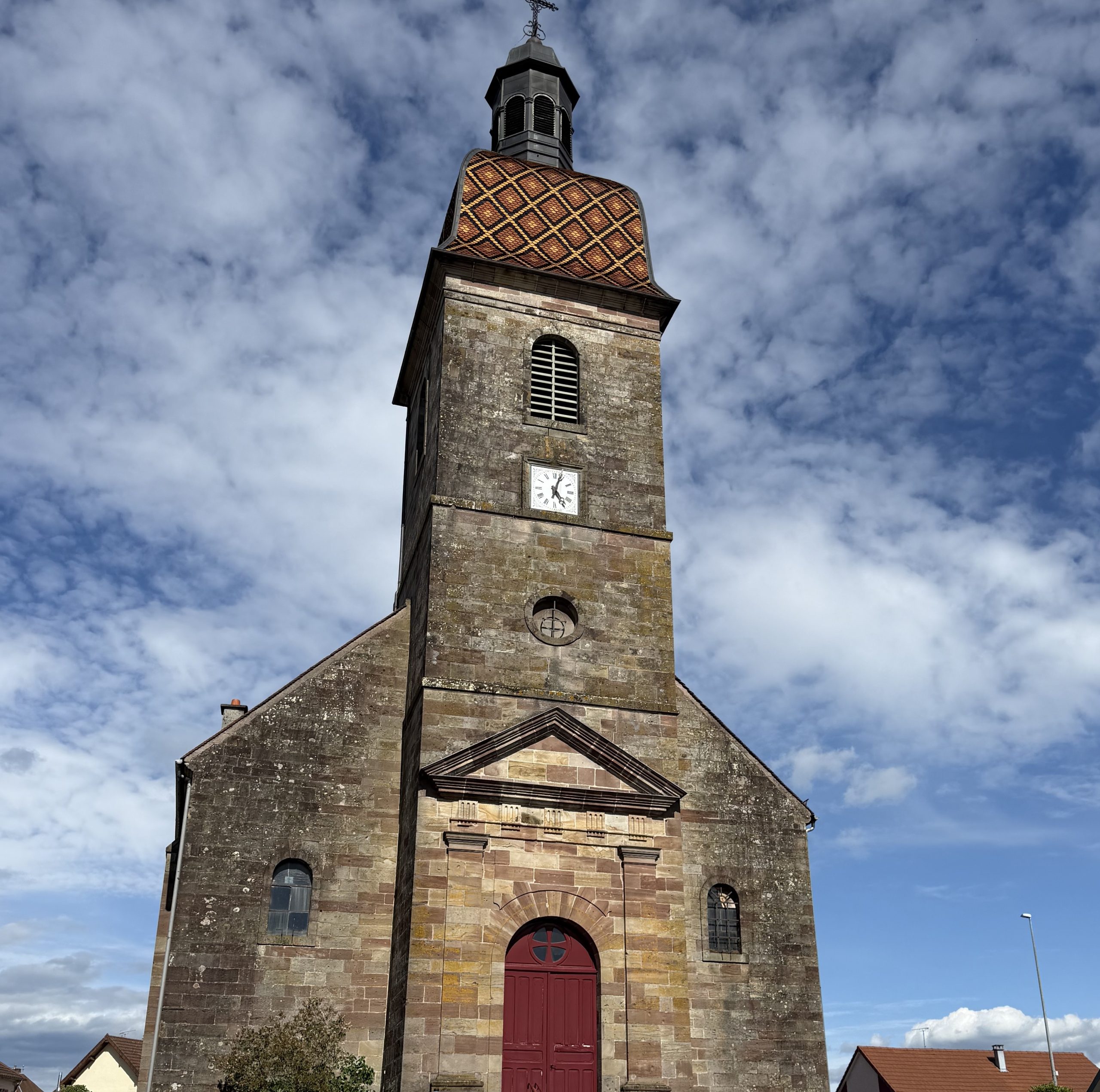 Façade et clocher-porche comtois à impériale de l'église Saint-Laurent à Champagney en Haute-Saône.